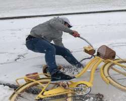 He tried to ride a bike in snow but fell down.